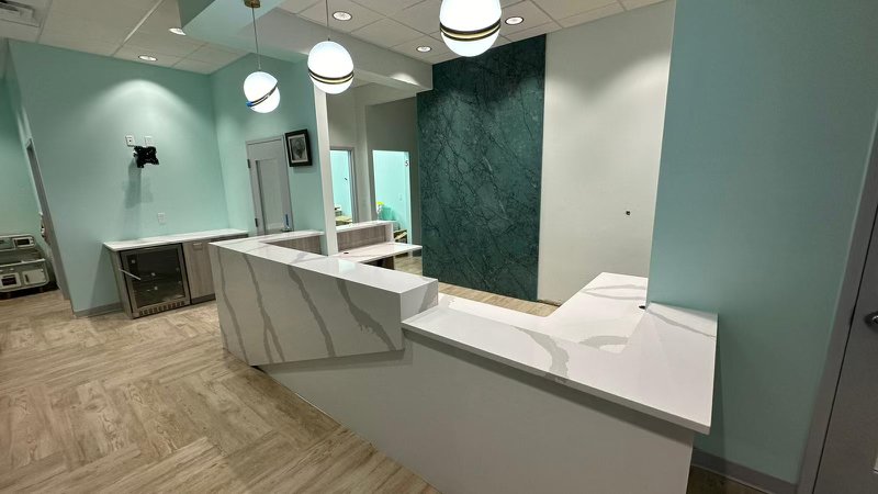 Commercial quartz reception desk with waterfall edge and green marble accent wall
