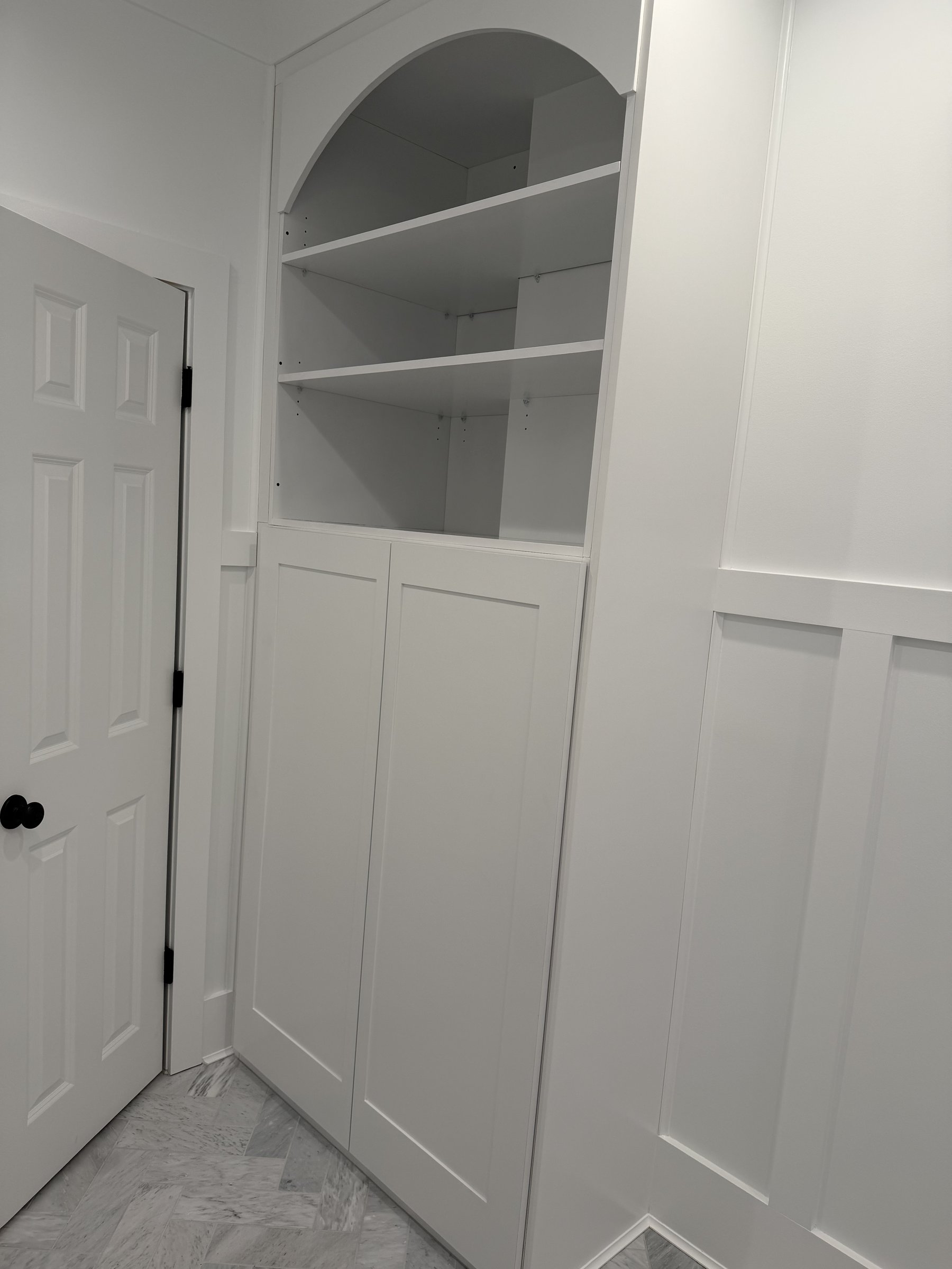 Custom arched built-in shelving with shaker doors
