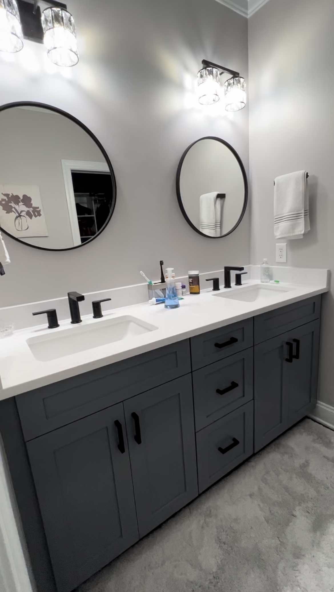 Grey bath vanity with round mirrors and crystal sconces
