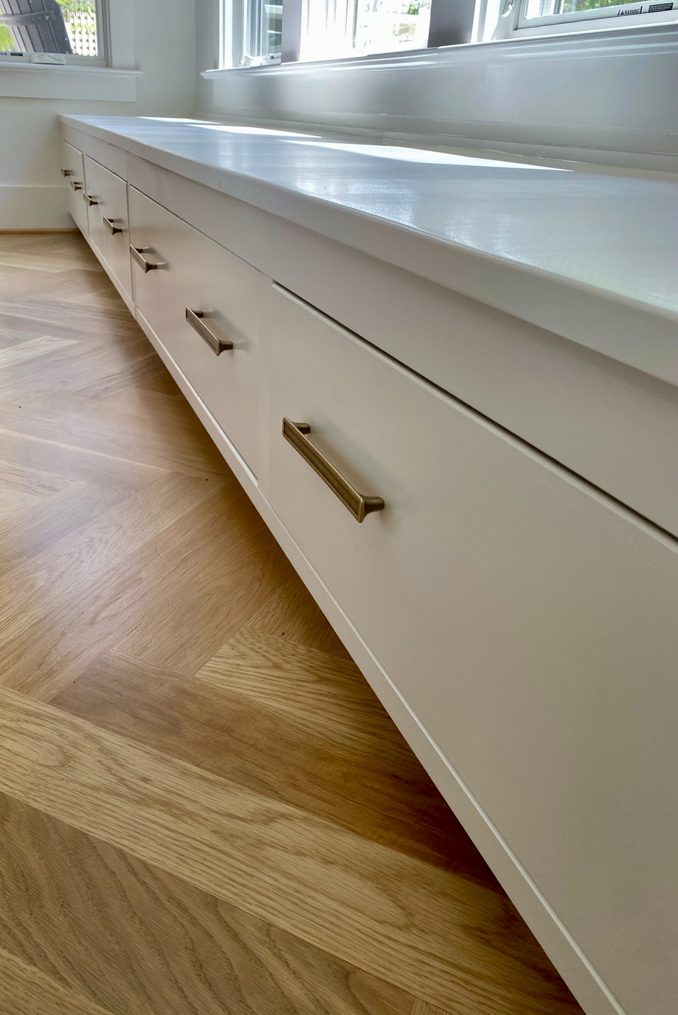 Window-seat built-in with brass pulls on herringbone floor